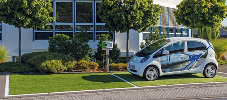 Der Grüne Parkplatz mit Ladesäule und Elektroauto